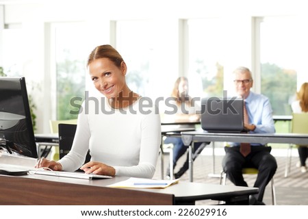 Middle age sales woman sitting at office and smiling.