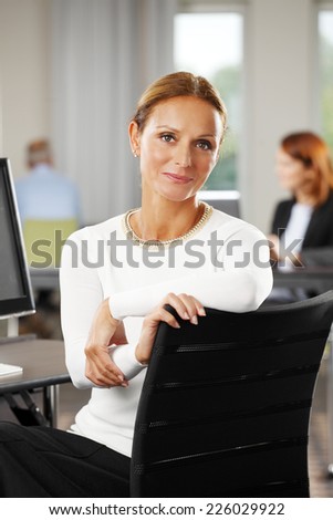 Portrait of beautiful middle age business woman sitting at office.