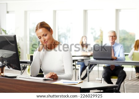 Beautiful business woman typing on computer while sitting at office.