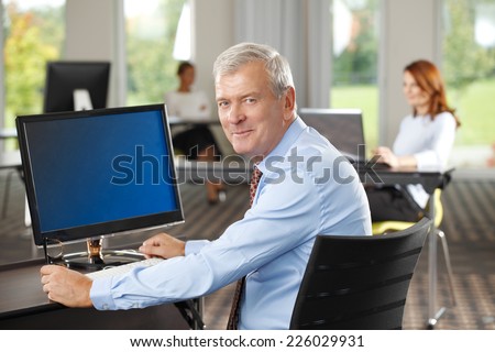 Close-up portrait of senior sales man sitting at office.