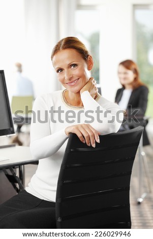 Portrait of executive middle age business woman sitting at office.