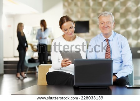 Portrait of executive old businessman working with business woman on laptop and digital tablet. Teamwork.