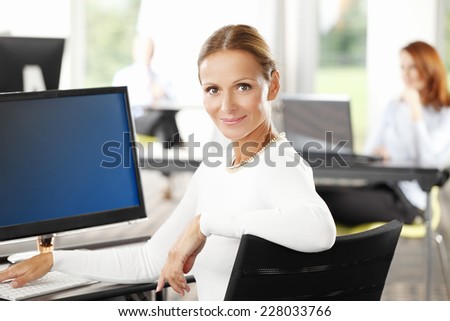 Close-up portrait of beautiful sales woman with laptop sitting at office. Business people.