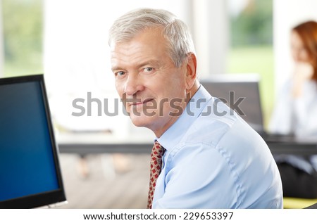 Close-up portrait of executive senior businessman sitting at office while using computer. Business people.