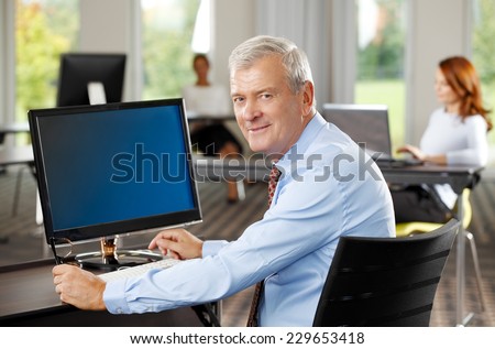 Portrait of executive old sales man sitting at office while using computer. Business people.