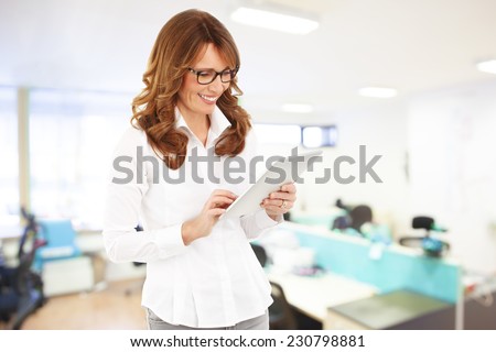 Portrait of confident business woman loading data on digital tablet.