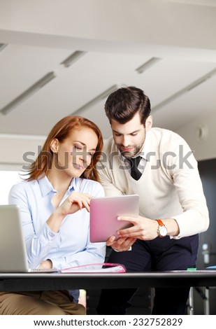 Young businessman holding digital tablet while discussing problems with executive business woman
