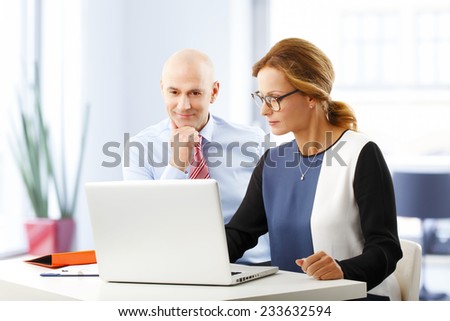 Portrait of efficiency business people analyzing data on laptop, while sitting at desk in bank.