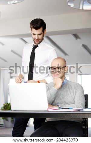 Executive businessman with laptop discussing idea with young sales man.