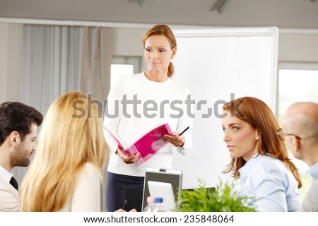 Portrait of middle age sales woman presenting her idea to sales team while they sitting at meeting