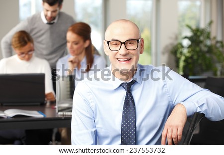 Close-up of chief financial officer sitting at office background with colleagues.