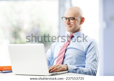 Portrait of satisfied sales man working on laptop and sitting at office.