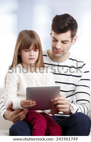 Young father studying his little daughter how to use internet safety at home.
