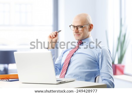 Confident businessman sitting in front of computer and thinking to solve the problem.