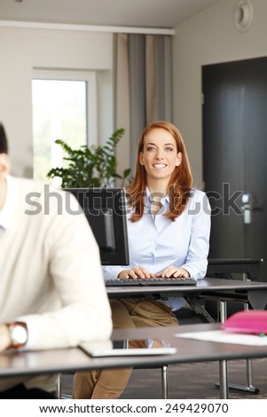 Portrait of middle age business woman sitting at office in front of computer.