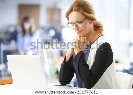 Portrait of mature business woman thinking about the solutions, while sitting in front of laptop at office.