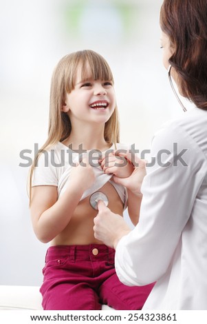 Portrait of female doctor listening to the heartbeat of cute girl.