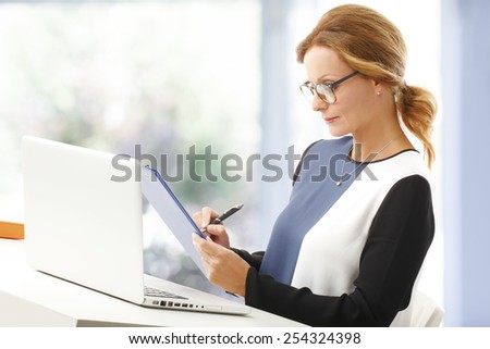Portrait of chief financial officer woman analyzing data while holding clipboard in her hands.