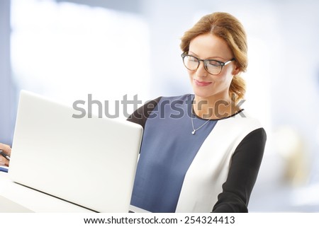Portrait of middle age business woman with laptop working at office.