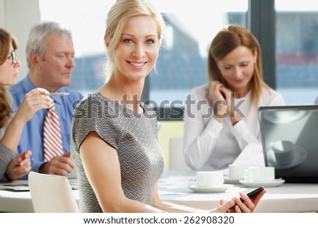 Portrait of female executive smiling and holding digital tablet in her hands while sitting at business meeting at office.