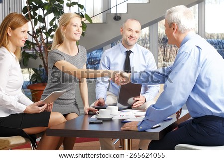 Business woman and businessman shaking hands while sitting at conference table at office. Successful business.