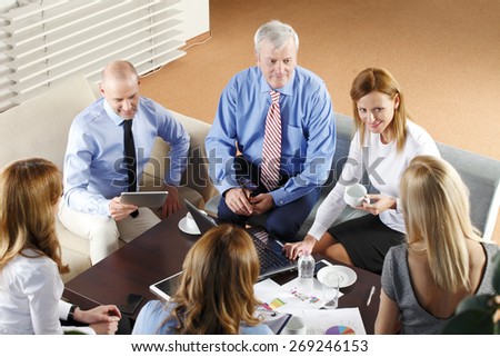 High angle view of business people sitting at meeting. Executive businesswoman presenting her idea to sales team while they are on staff meeting at office. Teamwork.