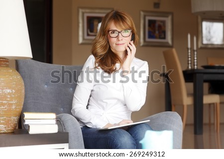 Portrait of busy businesswoman making telephone conversation while sitting and working at home. Home office.