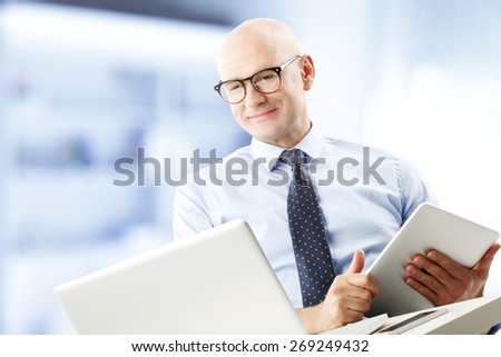 Portrait of chief financial officer holding financial report in hands while sitting in front of laptop and analyzing data. Businessman working at office.