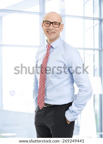 Portrait of middle age office manager wearing eyewear standing at office while looking at camera.