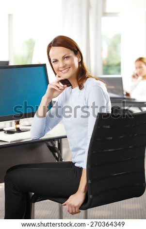 Portrait of smiling middle age sales woman sitting at office while looking at camera.