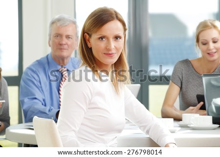 Executive businesswoman portrait. Close-up portrait of mature sales woman sitting at office while business team consulting at background.