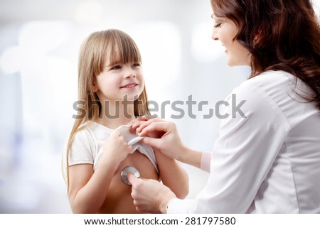Female doctor listening the heart break of preschool girl. Doctor and her patient sitting at surgery.