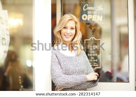 Small business. Portrait of confident female owner standing with arms crossed at shop facade.