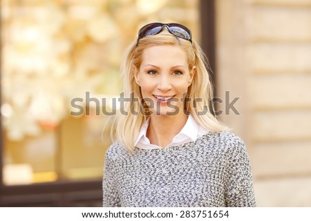 Close-up portrait of beautiful woman standing on the street while looking at camera and smiling.