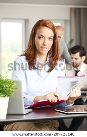 Portrait of executive businesswoman sitting at office in front of laptop and holding hands digital tablet. Mature woman touching the screen.