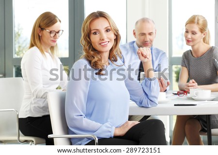 Portrait of attractive businesswoman sitting office while business people working at background. Group of business people consulting and analyzing financial data.