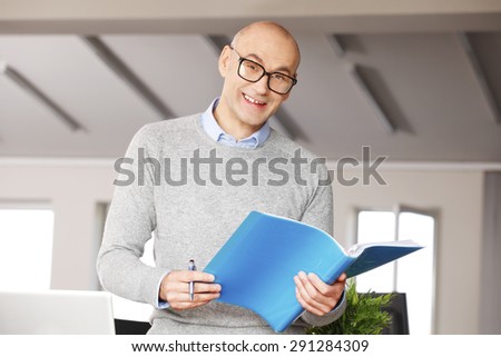 Portrait of financial director sitting at office in front of computer and working on business report.