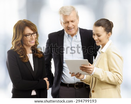 Portrait of young businesswoman standing with digital tablet and presenting her idea to business people. Teamwork at office.