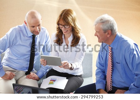 Portrait of financial manager holding digital tablet in her hands while consulting with sales men from annual report. Business team analyzing data at business seminar.
