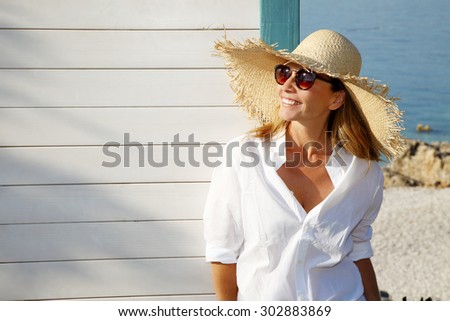 Close-up portrait of smiling female by the sea. Happy woman standing at the seaside and looking away.