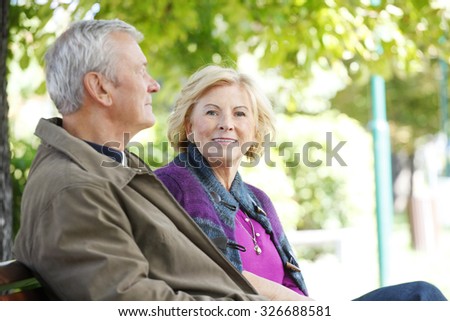 Senior couple relaxing at outdoors. Portrait of smiling elderly woman and friendly old man sitting togetherness at park and relaxing.