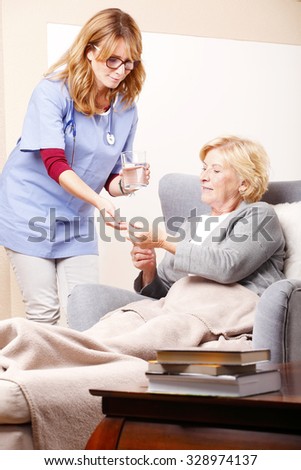 Portrait of senior woman sitting at home and home care nurse giving medication to an elderly woman