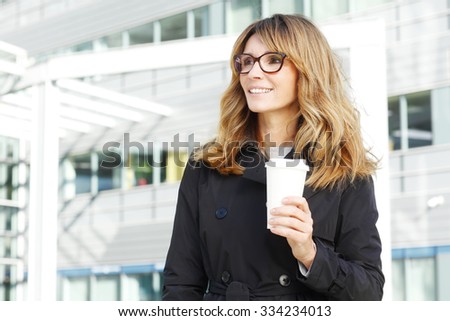 Portrait of financial professional woman holding in hand a cup of coffee while standing in front of office building after meeting.