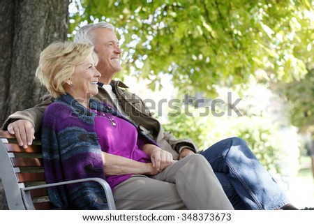Portrait of senior couple sitting on a bench outdoors while relaxing.