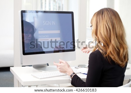 Rear view shoot of businesswoman sitting at her computer while log in and typing password to checking her bank account.
