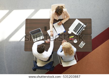 High angle shot of an investment advisor shaking hands with professional businessman while sitting on meeting.