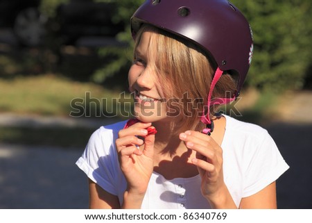 Close-up portrait of a young teenager girl buckle up her bicycle helmet