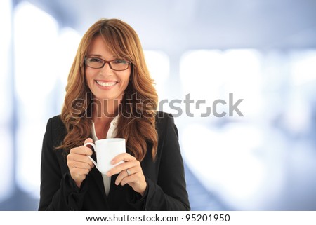 Beautiful mature woman drinking a cup of coffee in her office. (with copy space.)
