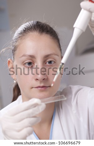 Woman dropping blood drop on sample glass with micro pipette