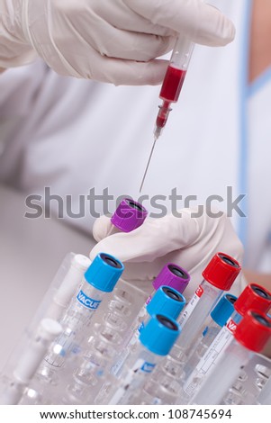 Woman injecting blood in test tube. Laboratory environment